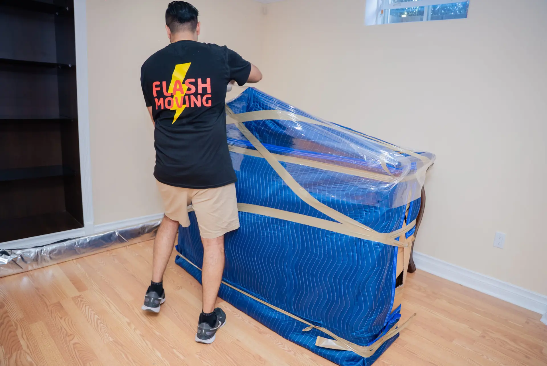 Flash Moving crew member securing blanket-wrapped china cabinet with packing tape in Mississauga home